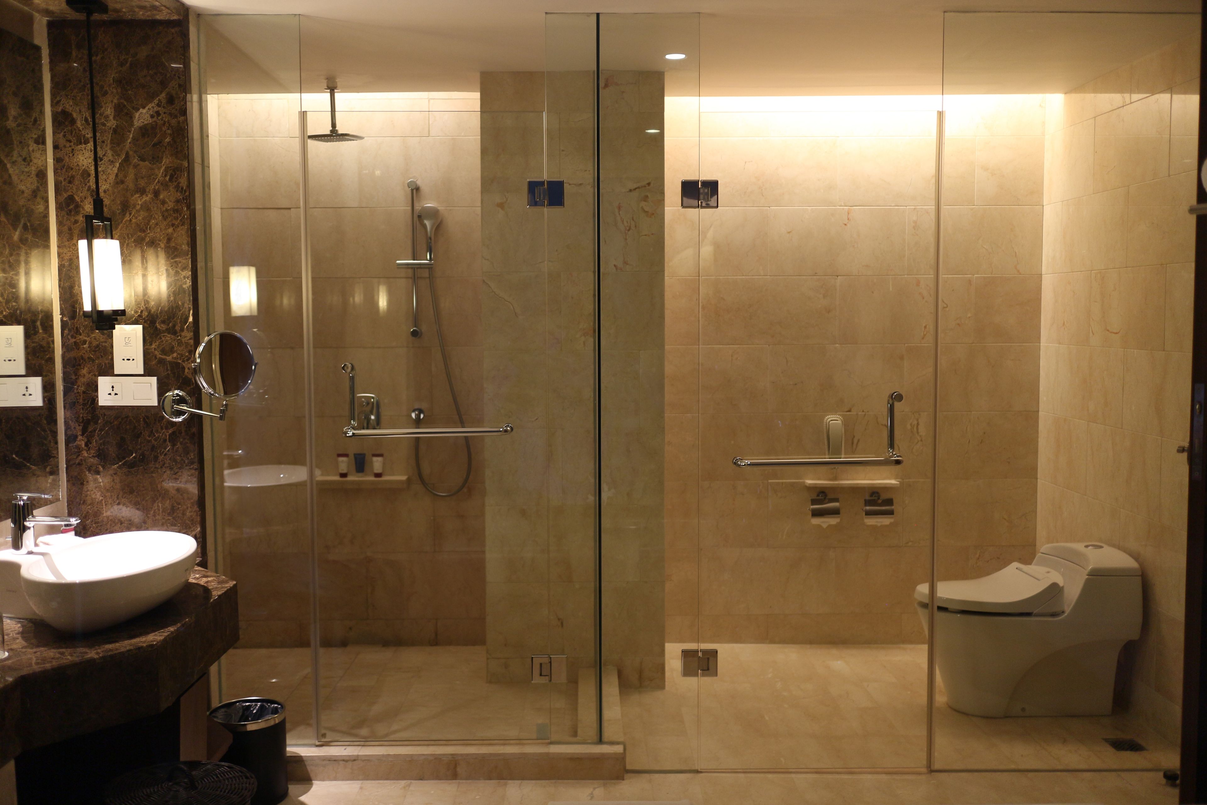 A modern bathroom with a glass-enclosed shower, a white sink, and a toilet.
