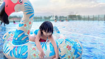 Un niño sobre un cisne inflable con motivos florales en una piscina.