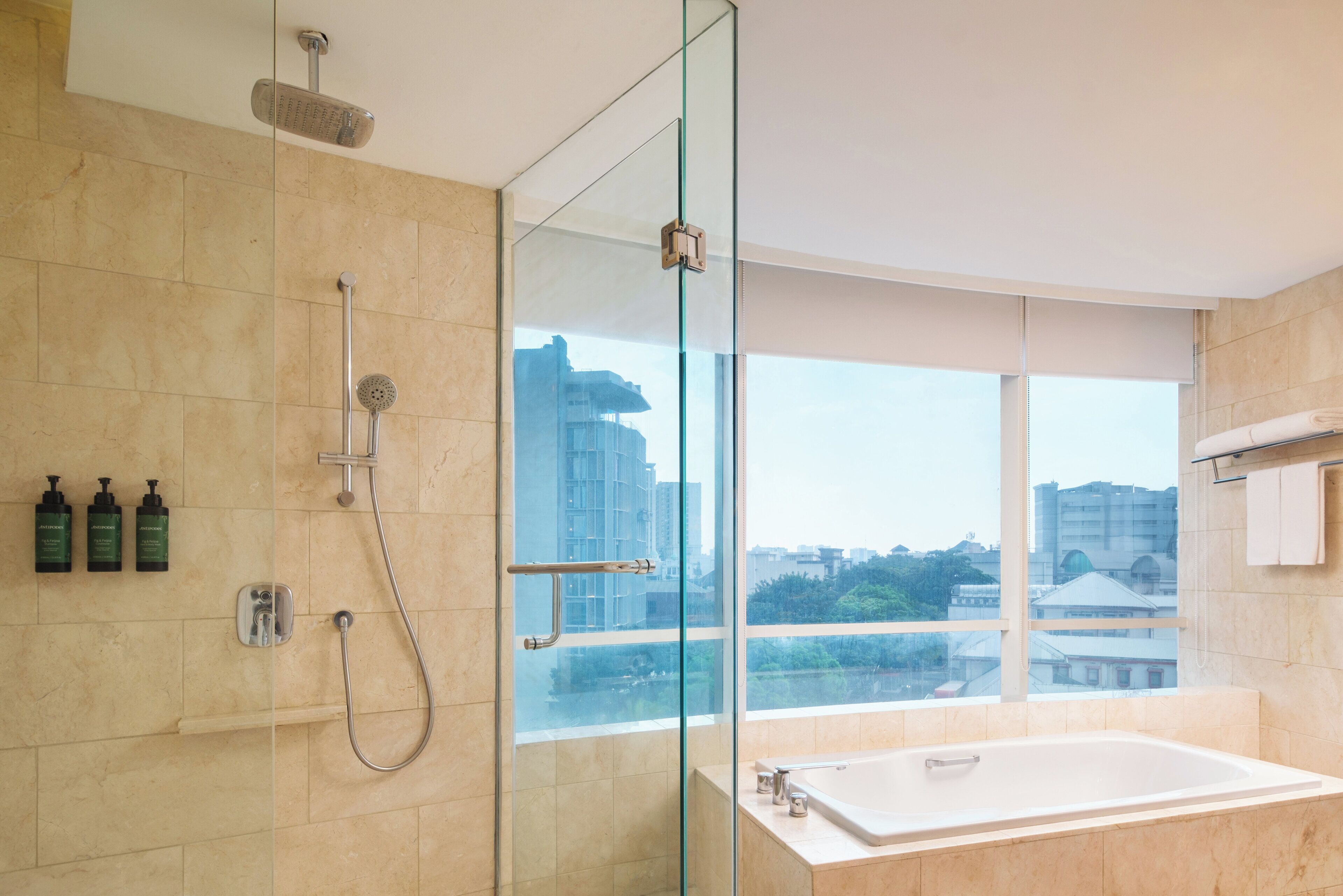 Un baño moderno con ducha de vidrio, un ventanal grande y una bañera.