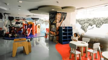 A children's play area with colorful play structures and a mural on the wall.