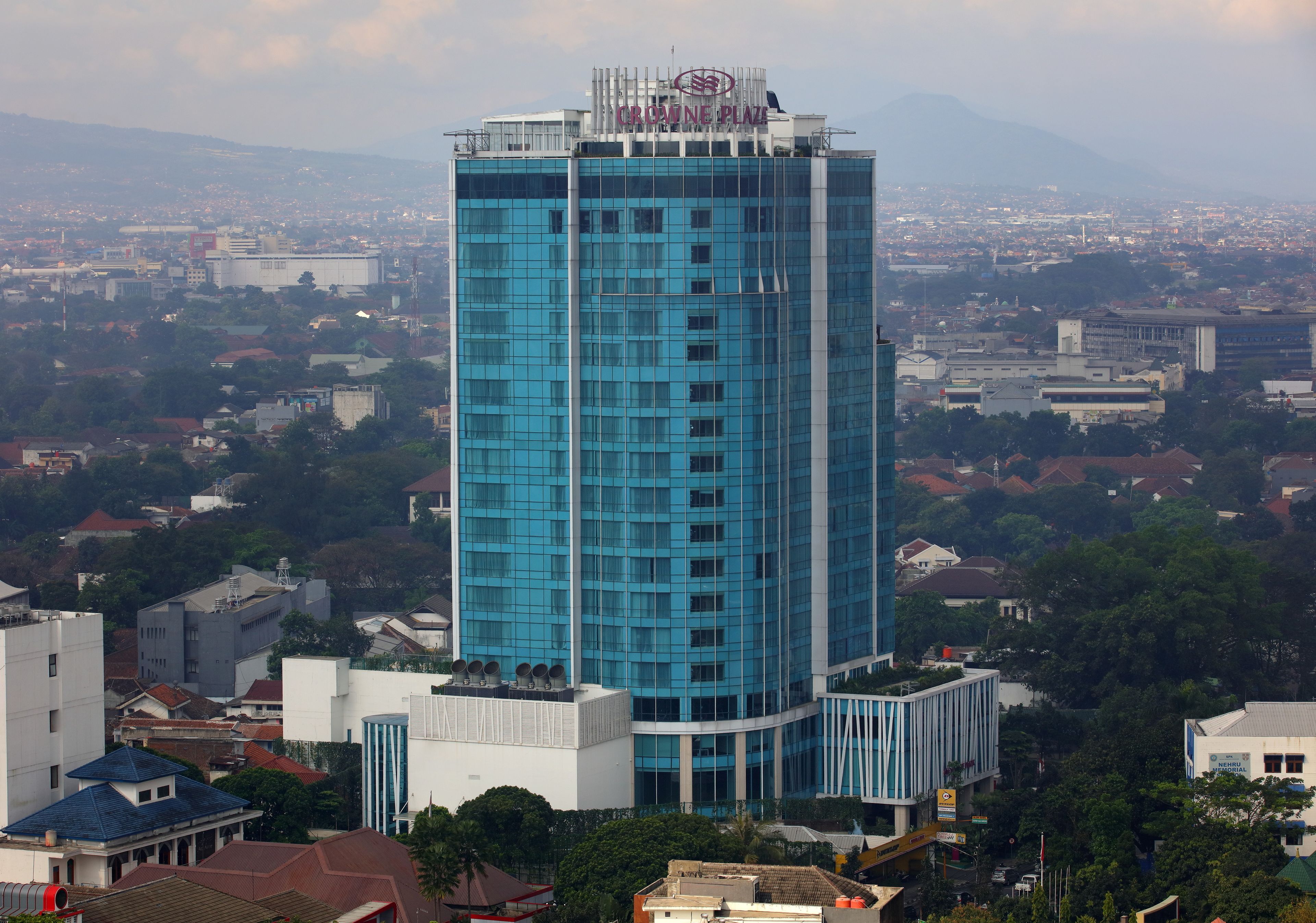 A tall blue glass building with a sign reading "CARPINE PLAZA" at the top.