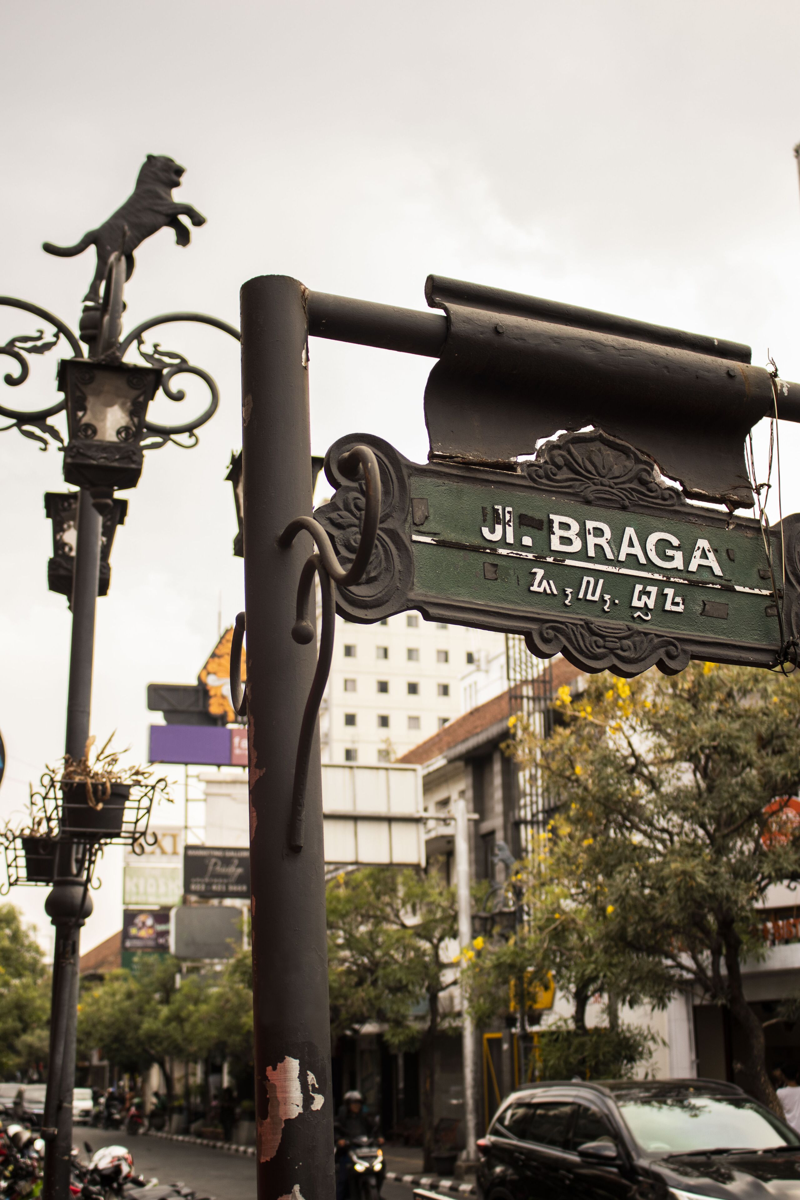 A street sign with the name "JI. Braga" and a lion statue.