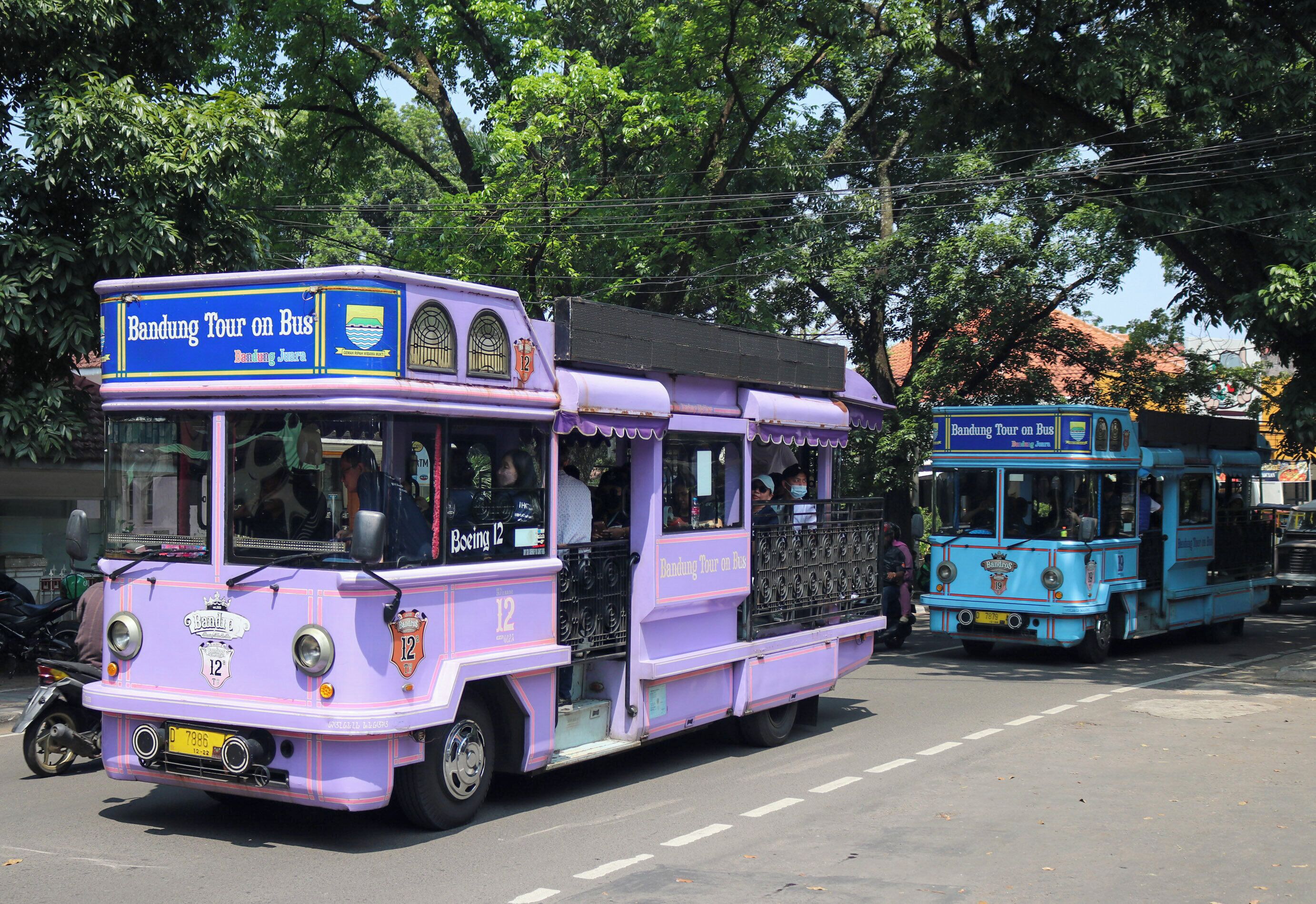 A purple and blue bus with 'Bandung Tour on Bus' written on it, parked on a street.