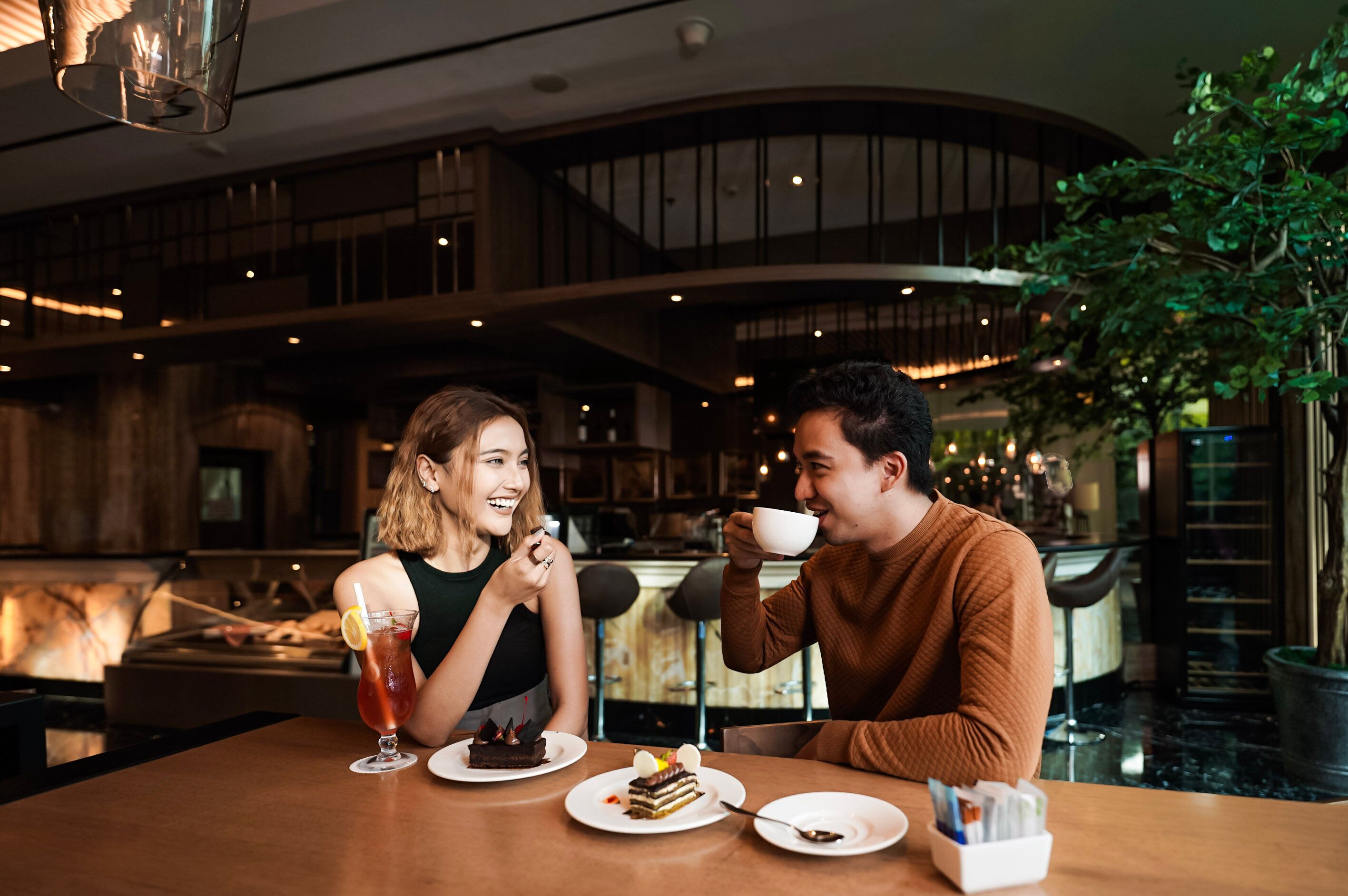 A couple dining in a modern restaurant with a high ceiling and exposed beams.