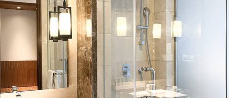 Un baño moderno con ducha envuelta en vidrio, un espejo grande y un tocador con lavabo y perchero para toallas.