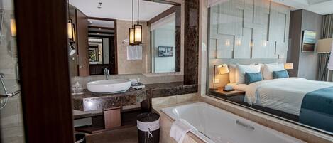 A modern bathroom with a large bathtub, a vanity with a sink, and a mirror.