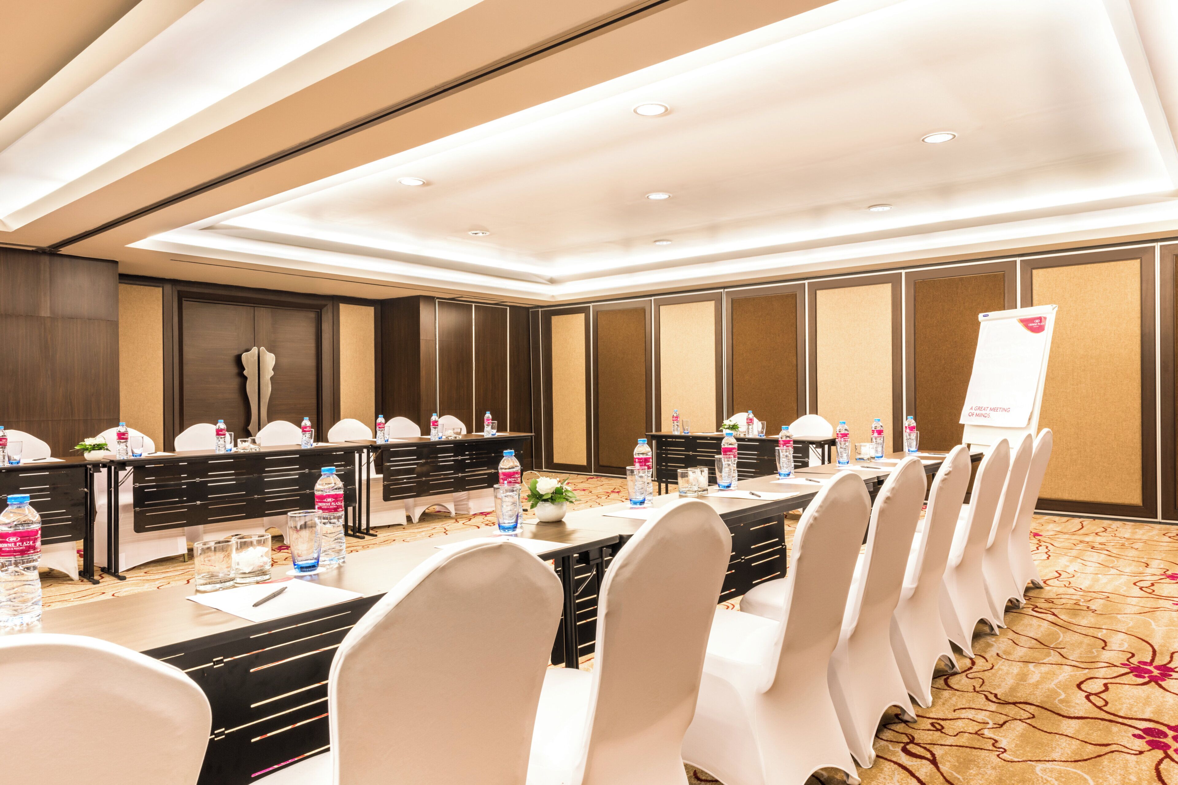 A conference room with a long table, chairs, water bottles, and a sign indicating a great meeting.