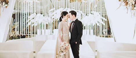 Une cérémonie de mariage où les mariés se tiennent devant un décor floral.