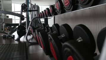 Un gimnasio con hileras de mancuernas y máquinas de pesas.