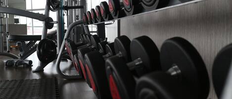 Un gimnasio con hileras de mancuernas y máquinas de pesas.