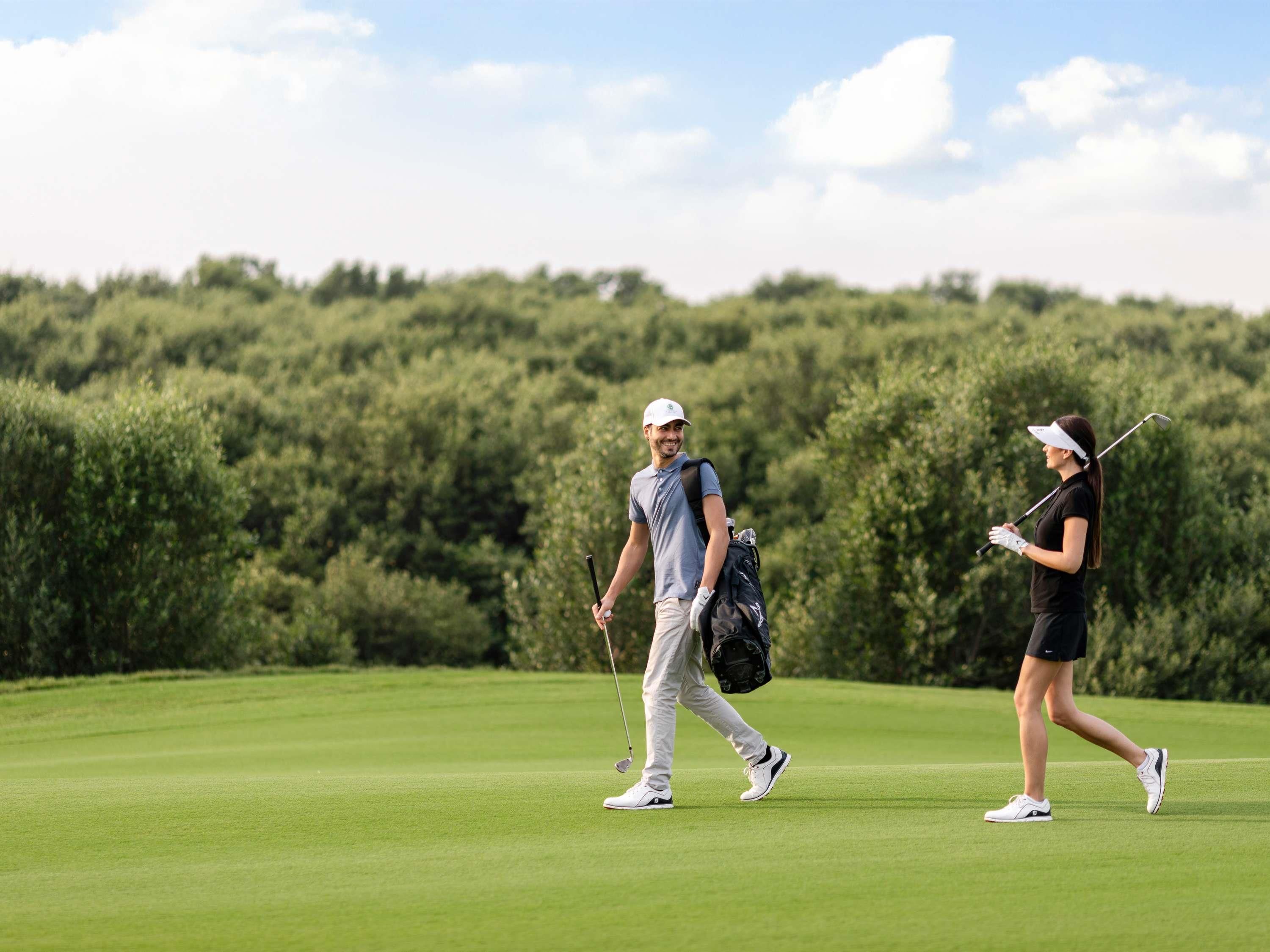 Un parcours de golf doté d’un terrain verdoyant bien entretenu et bordé d’une forêt.
