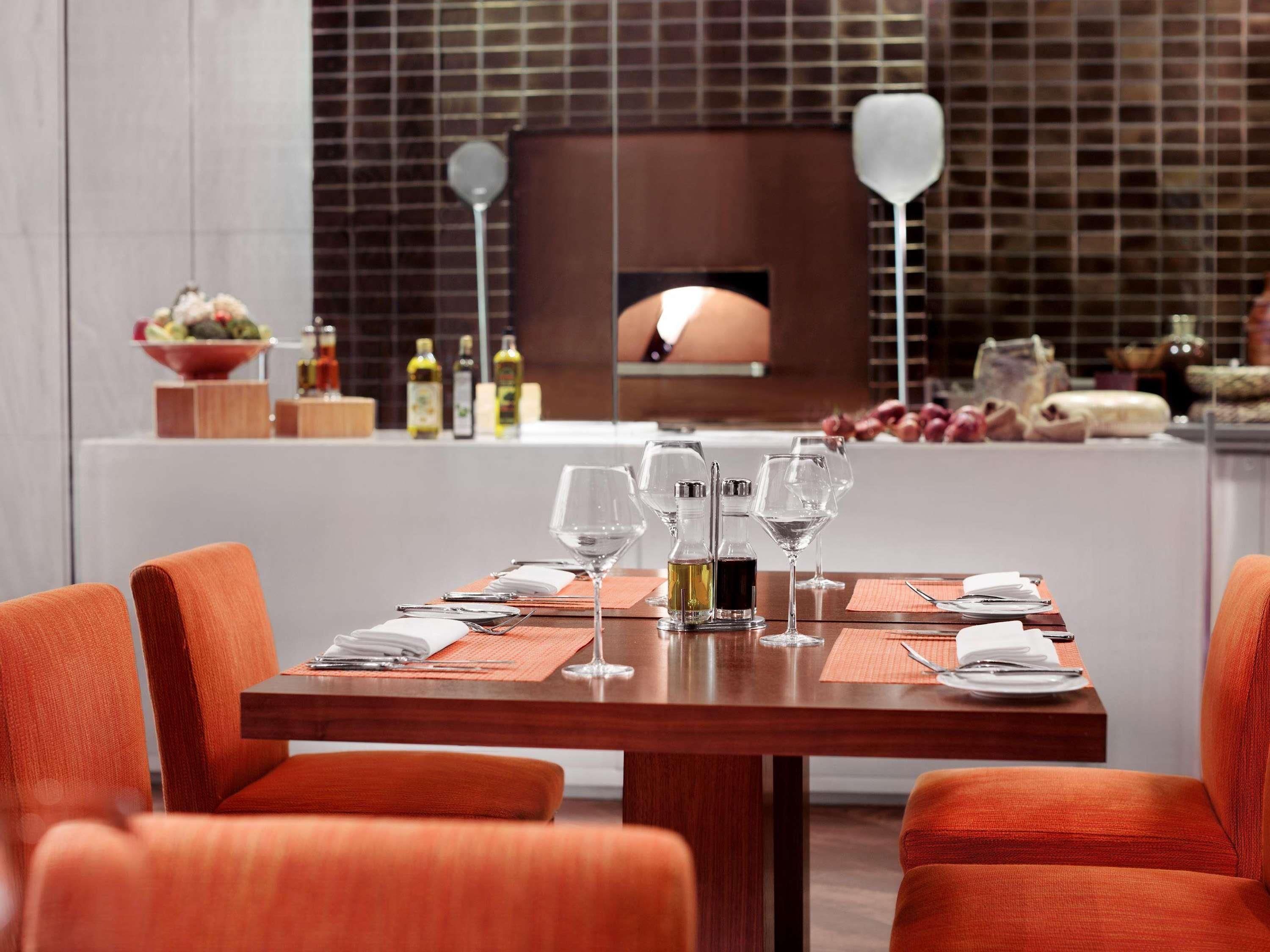 A dining area with a wooden table set for two, equipped with wine glasses, cutlery, and condiments.