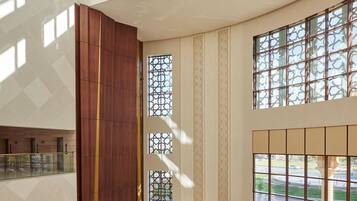 Un amplio vestíbulo con techos altos, ventanas grandes y una zona de recepción con escritorio y sillas.