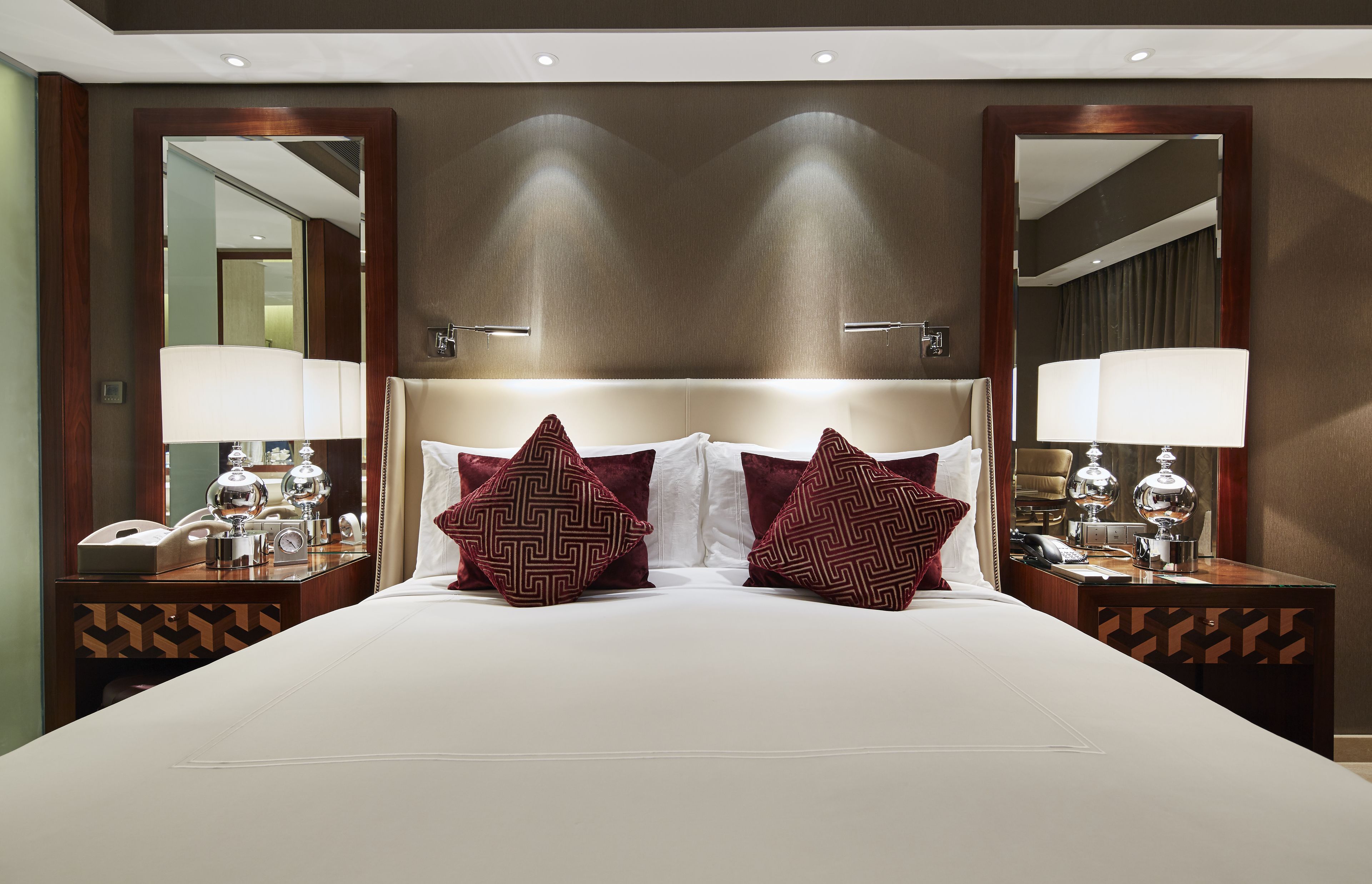 A large bed with two decorative pillows, a headboard, and two bedside tables with lamps and a phone.