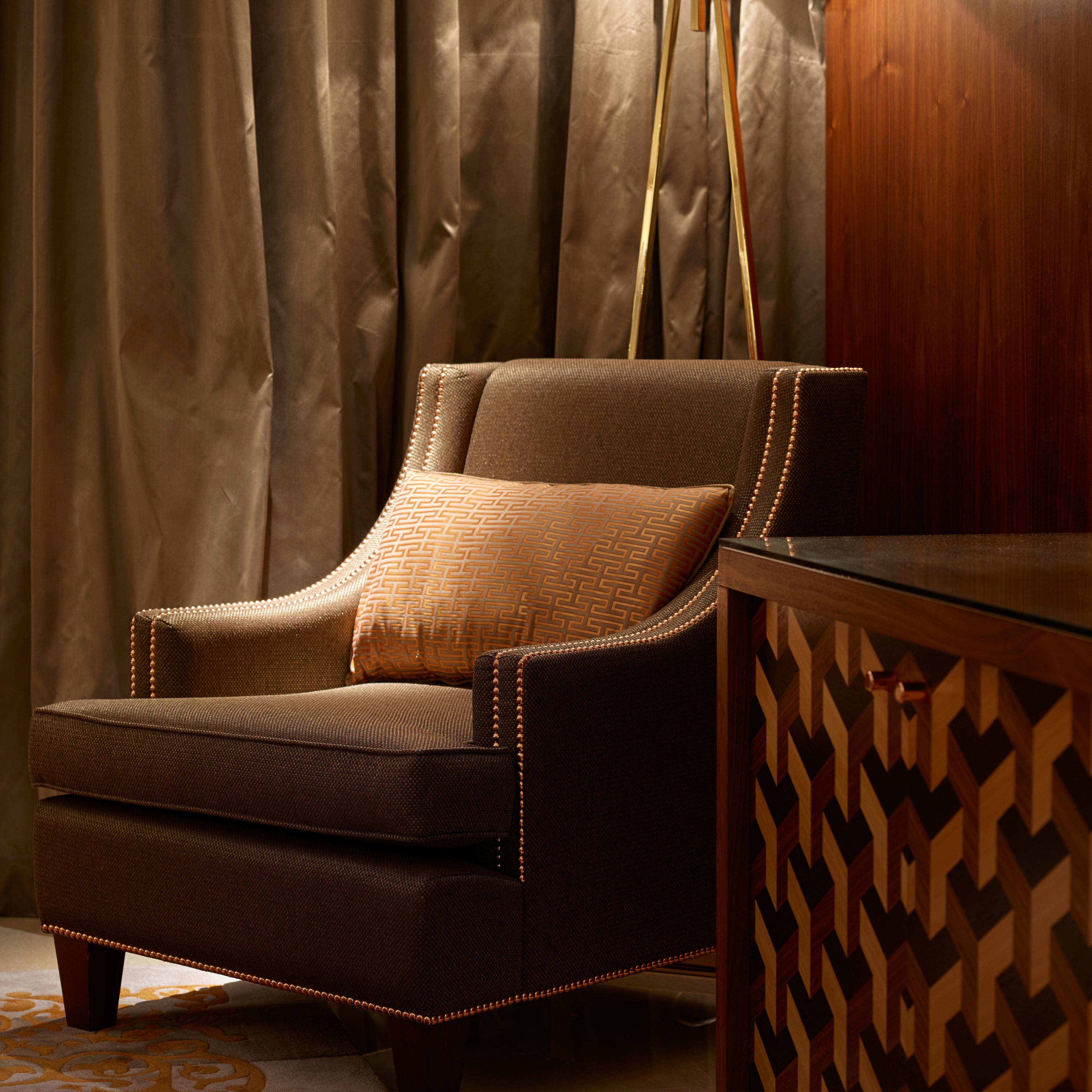 A brown armchair with a patterned cushion, positioned in front of a wooden side table with a geometric design.
