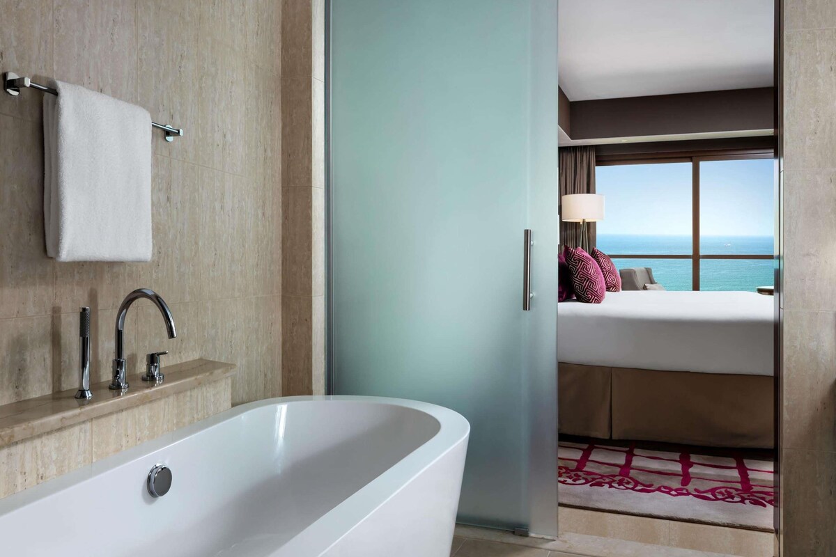A modern bathroom with a freestanding bathtub, a towel rack, and a shower with chrome fixtures.