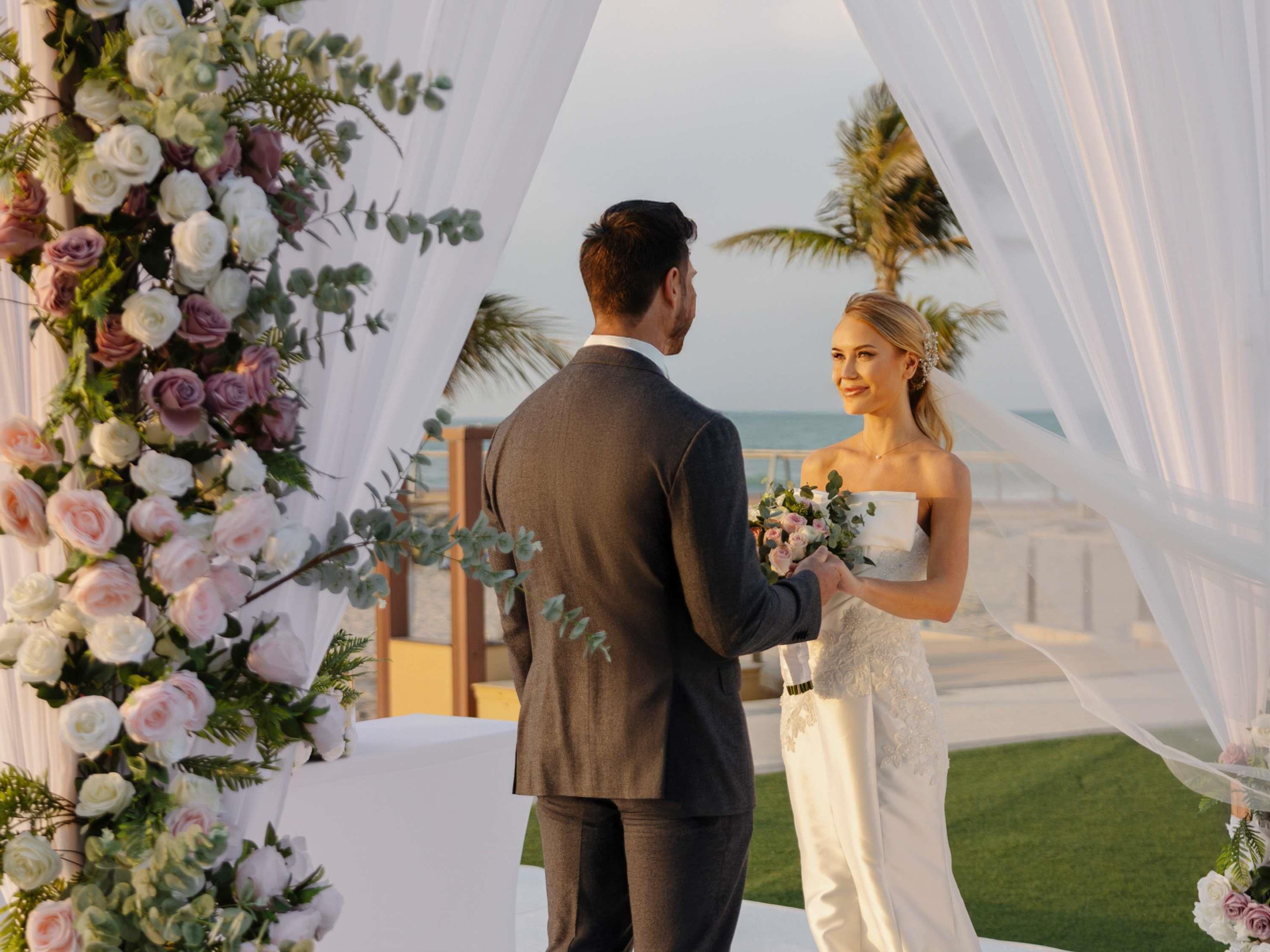 Une cérémonie de mariage où les mariés se tiennent sous une arche décorée de fleurs.