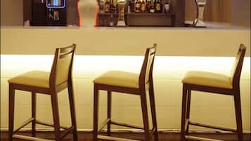 Una zona de bar con sillas de madera y una barra que exhibe varias botellas.