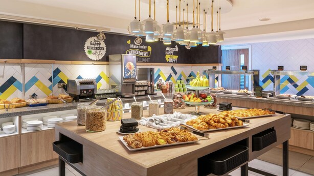Ein Buffet mit verschiedenen Speisen, einer Kaffeemaschine und einer Wand mit motivierenden Zitaten.