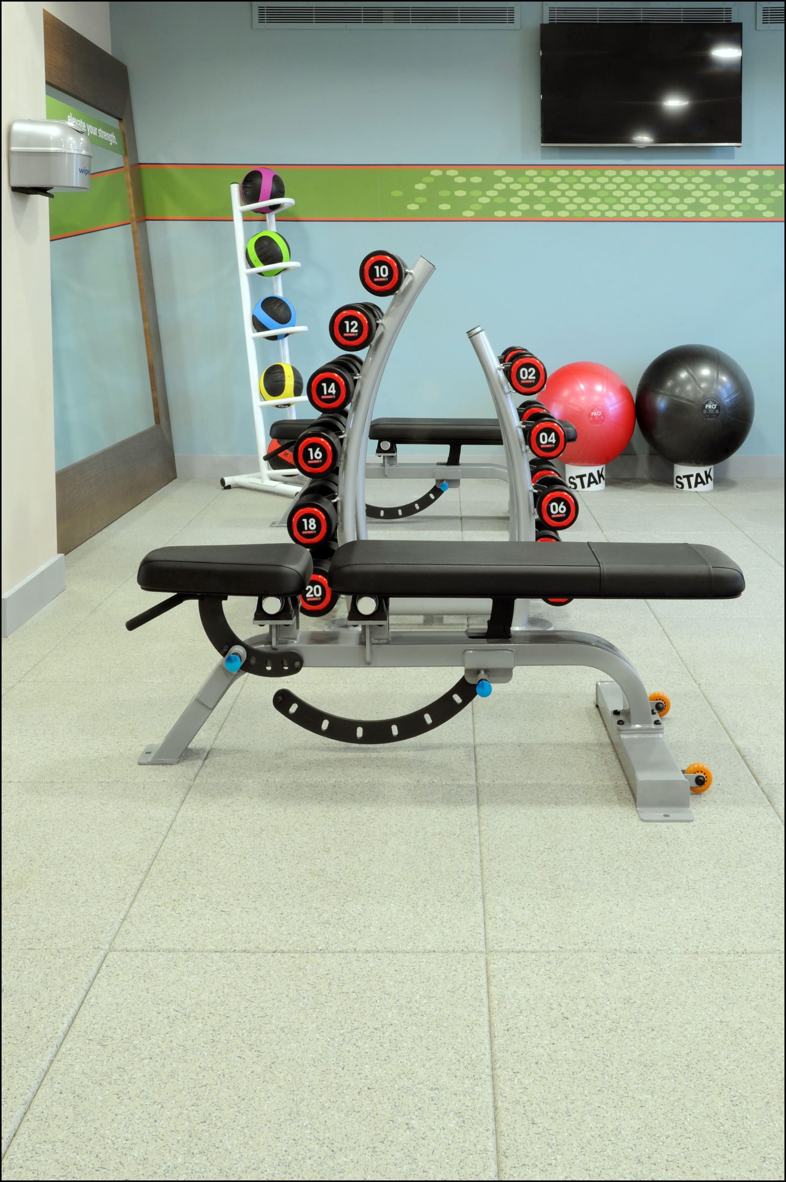 Ett gym med en bänkpress, hantlar och träningsbollar.