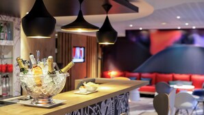 Una zona de bar con una copa de champán, una barra de madera e iluminación colgante moderna.