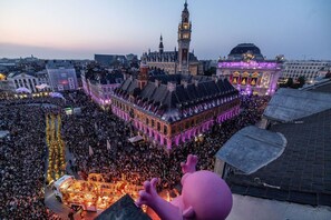 Una gran multitud se reunió alrededor de un edificio histórico con una torre de reloj, rodeado de otras estructuras destacadas.