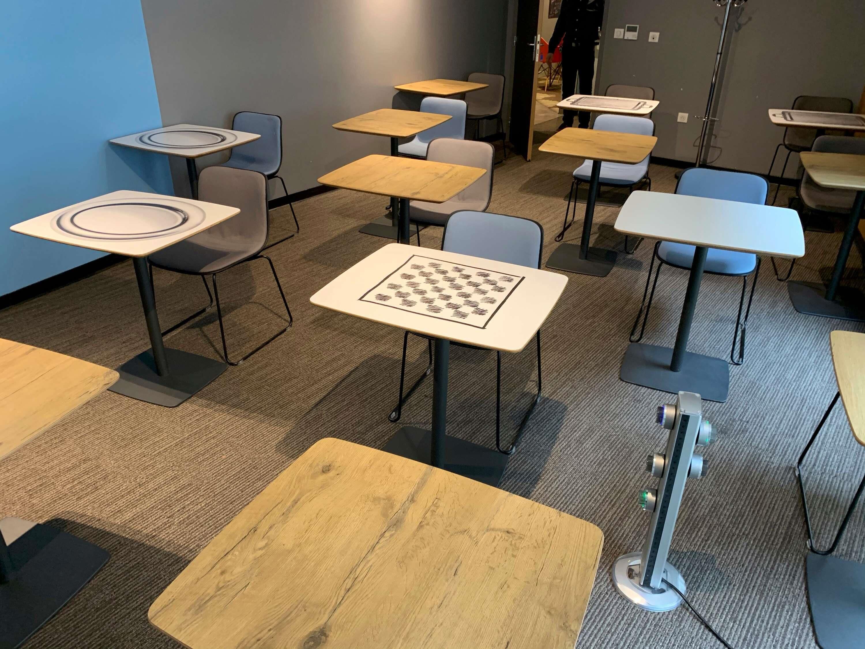 A room with multiple tables and chairs, a chessboard on one table, and a projector stand.