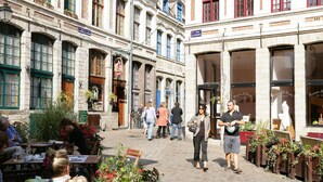 Una calle adoquinada con edificios que tienen grandes ventanales y terrazas al aire libre.