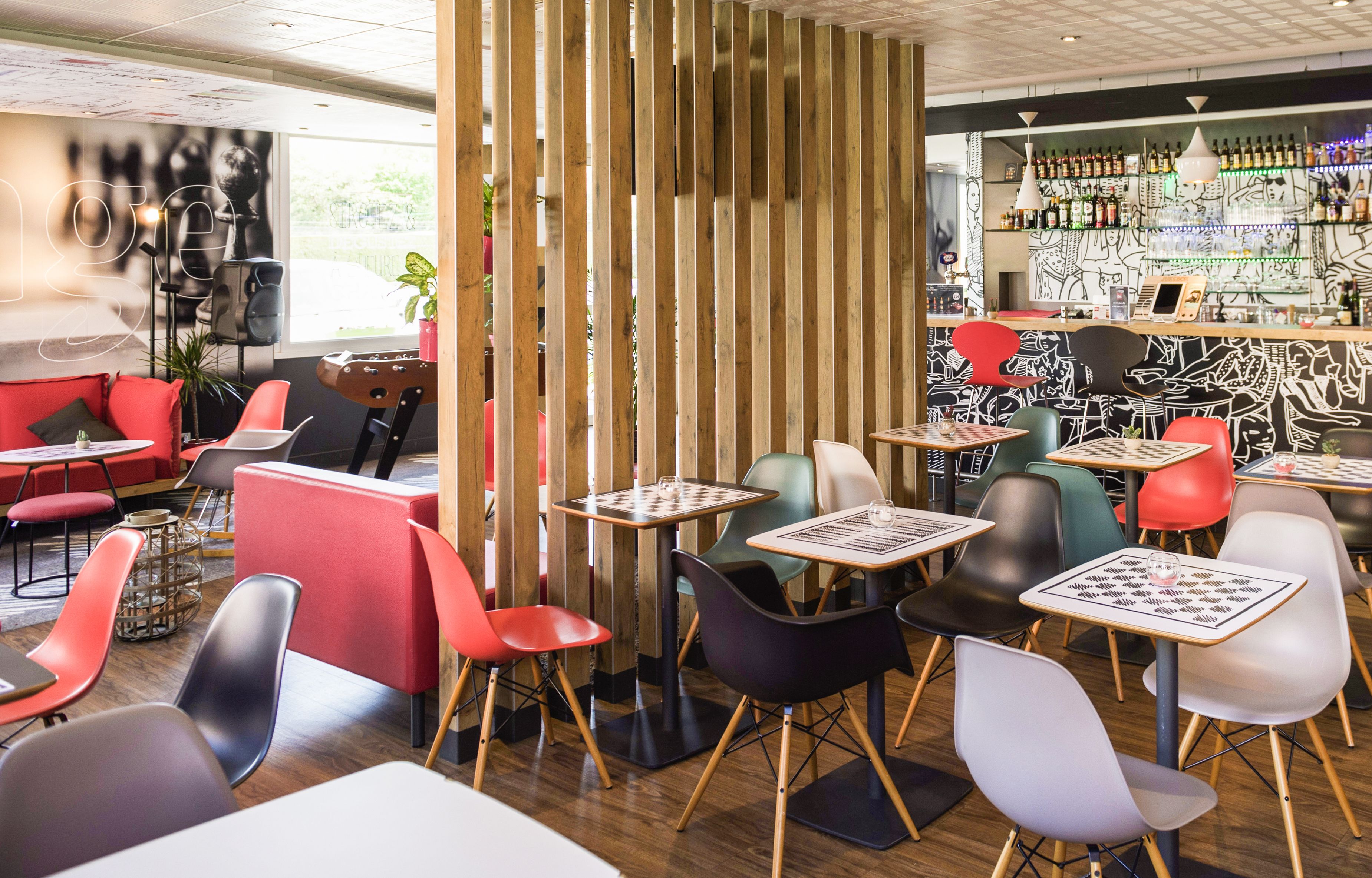 Café moderno com divisórias de madeira, cadeiras coloridas e um espaço de bar com vários tipos de garrafas.