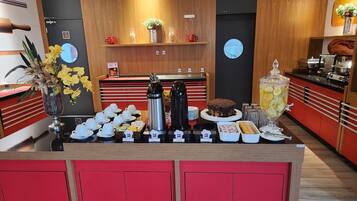Morgenmadsbuffet med kaffemaskiner, tepotter og et udvalg af mad.