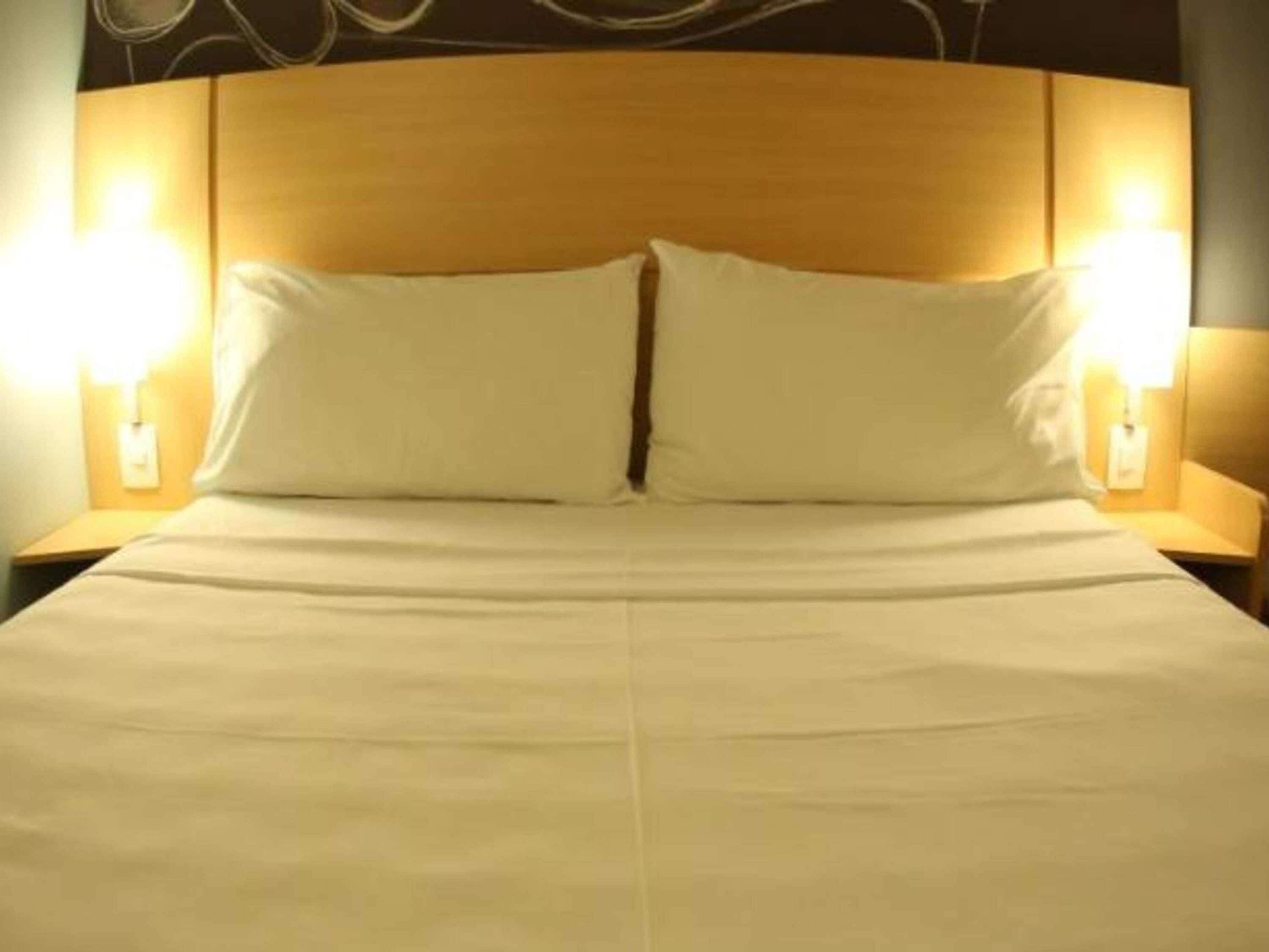 Una cama con dos almohadas y dos lámparas de noche.