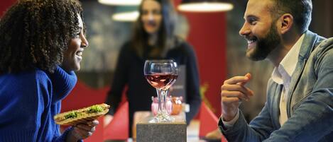 Un restaurante con una mesa, comida y una copa de vino tinto.