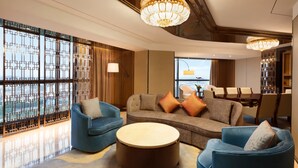 A modern living room with a sofa, two armchairs, a round coffee table, and a dining area with a table and chairs. - Ramada Foshan Nanhai (Foshan)