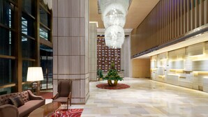 A lobby with a tufted sofa, a round table, a potted plant, and a patterned rug. - Ramada Foshan Nanhai (Foshan)