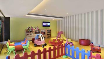 A children's play area with colorful toys and a TV screen displaying 'TOM Jolly'.
