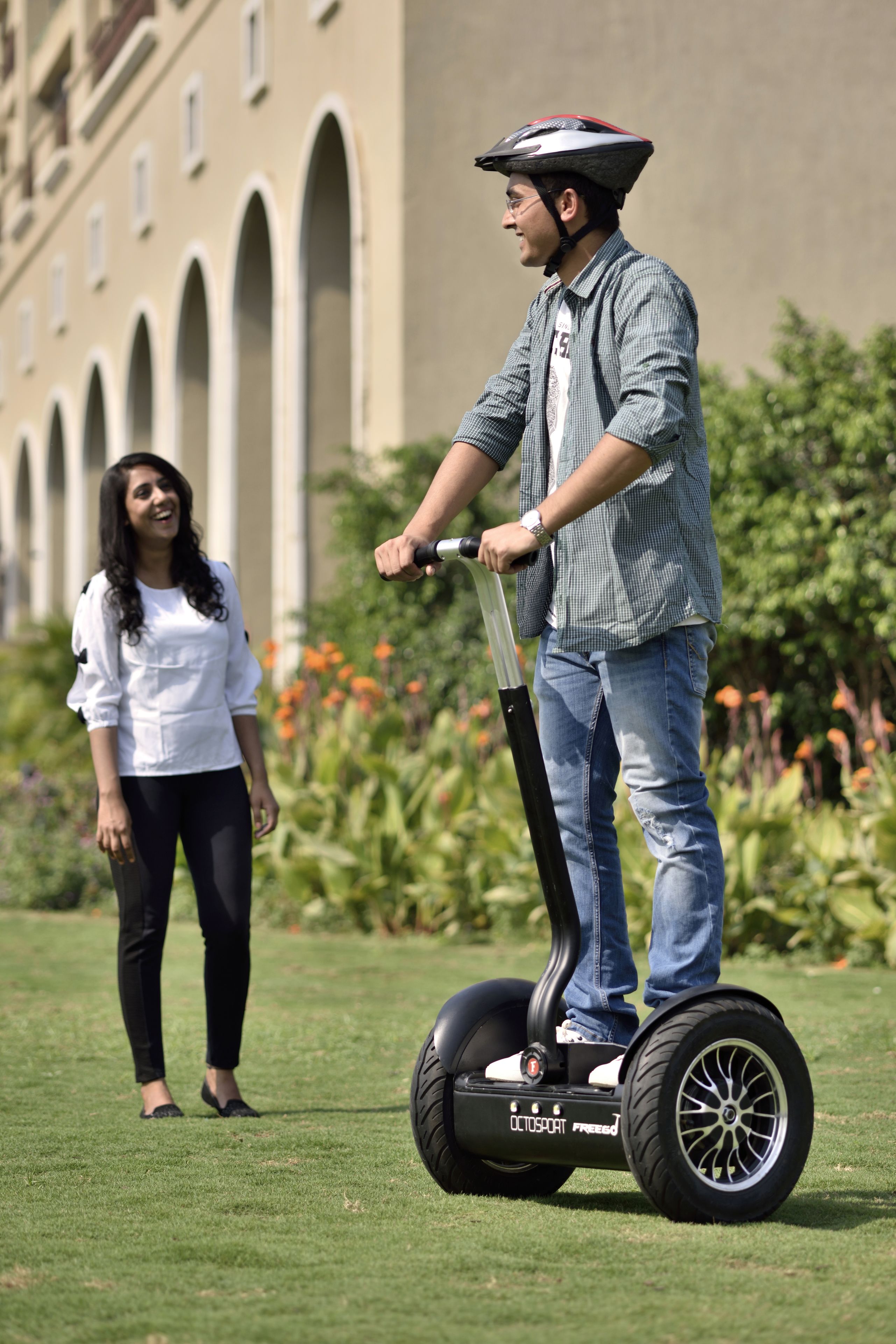 Una persona montando un Segway sobre un área cubierta de césped con un edificio al fondo.
