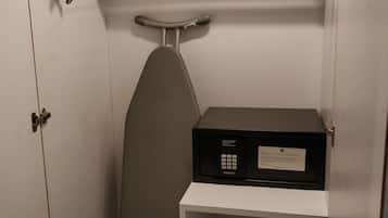 A compact room with a white wardrobe, a small ironing board, and a compact iron.