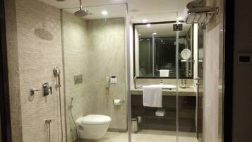 Un baño moderno con ducha envuelta en vidrio, inodoro y lavabo con espejo.