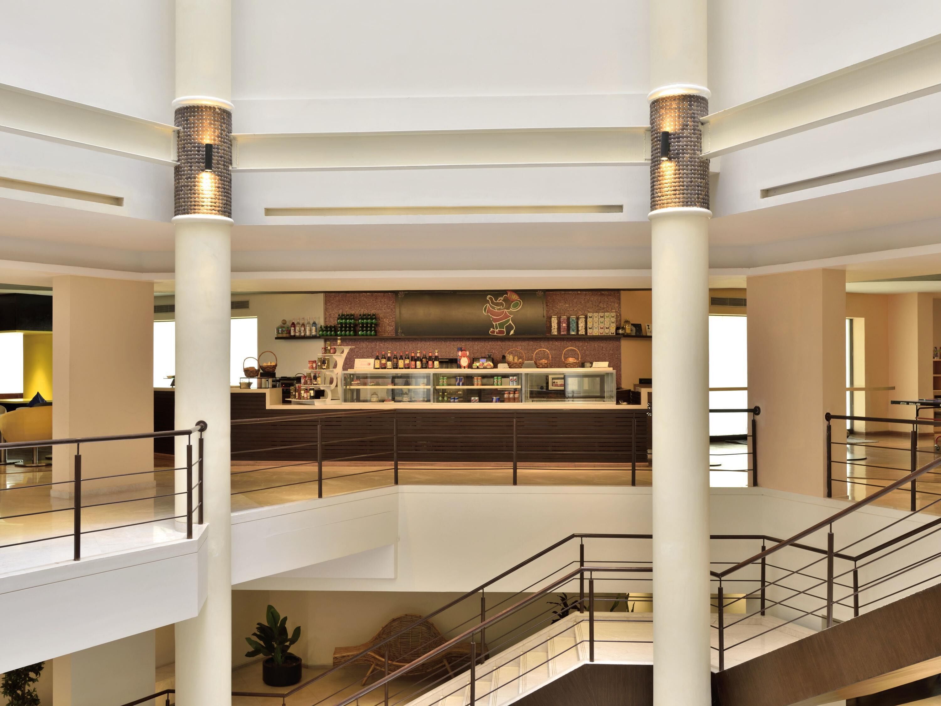 A multi-level hotel lobby with a central bar area, multiple floors, and a staircase.