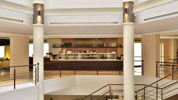 A multi-level hotel lobby with a central bar area, multiple floors, and a staircase.