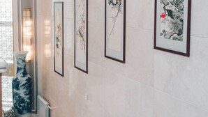 Ein Flur mit vier gerahmten Kunstwerken an der Wand, einer Vase und einem Heizkörper.