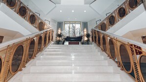 Eine prächtige Treppe mit aufwendig verzierten goldenen Geländern und einem Schiffsmodell am oberen Ende.