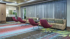 A hotel lobby with a sofa, chairs, a small table, and a colorful carpet. - Hilton Garden Inn San Antonio At The Rim (San Antonio)