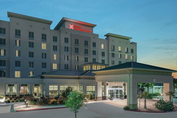 A hotel with a modern design, featuring a prominent entrance with a covered area and a sign indicating the name. - Hilton Garden Inn San Antonio At The Rim (San Antonio)
