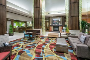 A spacious lobby with a patterned carpet, seating areas, and a fireplace. - Hilton Garden Inn San Antonio At The Rim (San Antonio)