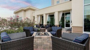 An outdoor seating area with wicker furniture and a fire pit. - Hilton Garden Inn San Antonio At The Rim (San Antonio)