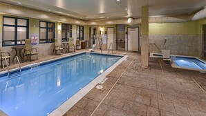 A large indoor pool with clear blue water, surrounded by lounge chairs and a tiled floor. - Hampton Inn Hibbing (Hibbing)