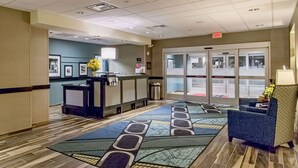 A hotel lobby with a reception desk, a patterned carpet, and a seating area. - Hampton Inn Hibbing (Hibbing)