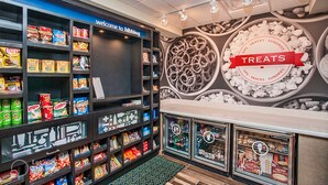 A snack display area with shelves stocked with various snacks and a wall with a 'TREATS' sign. - Hampton Inn Hibbing (Hibbing)