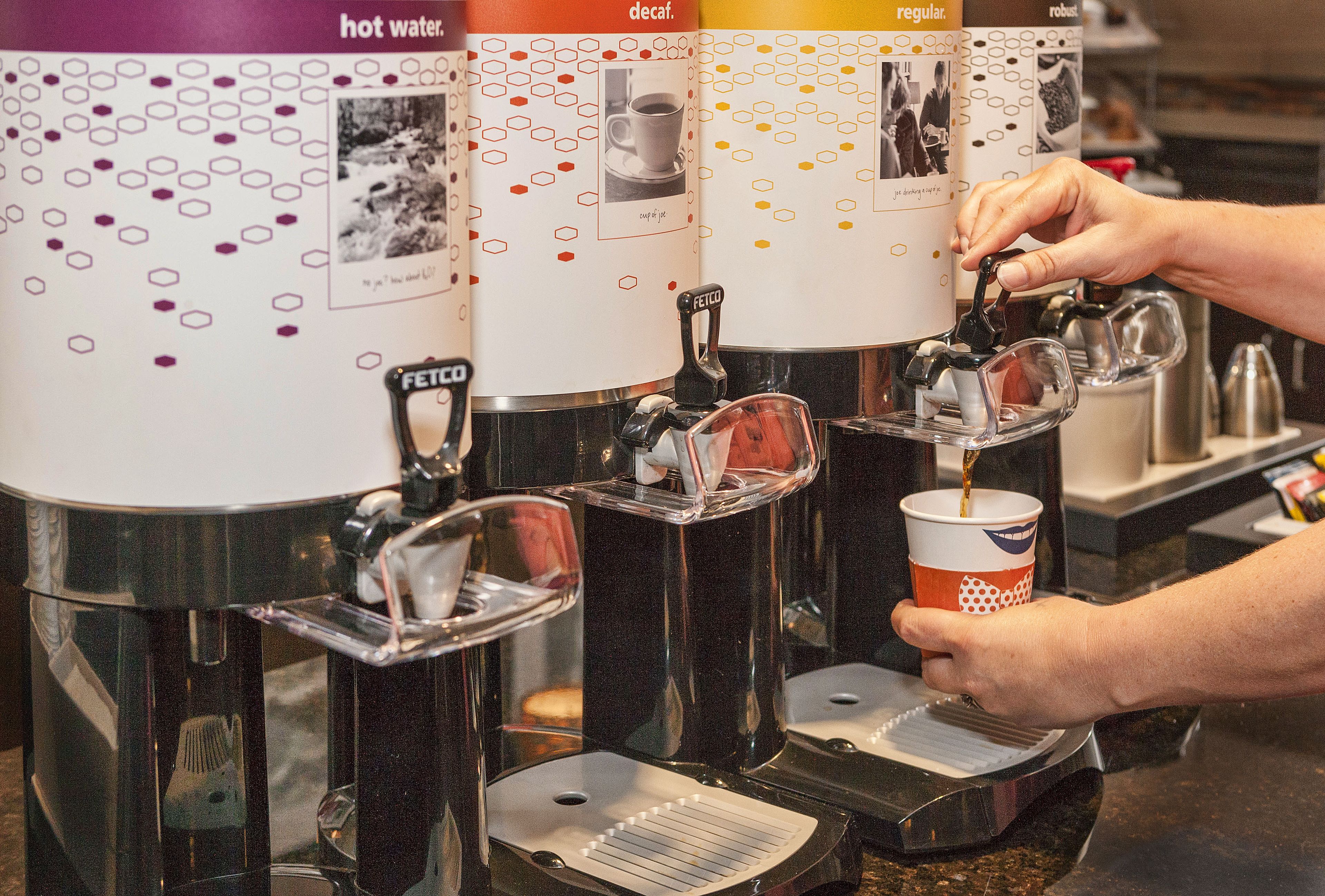 Una cafetera con varios dosificadores, cada uno etiquetado con distintos tipos de café.